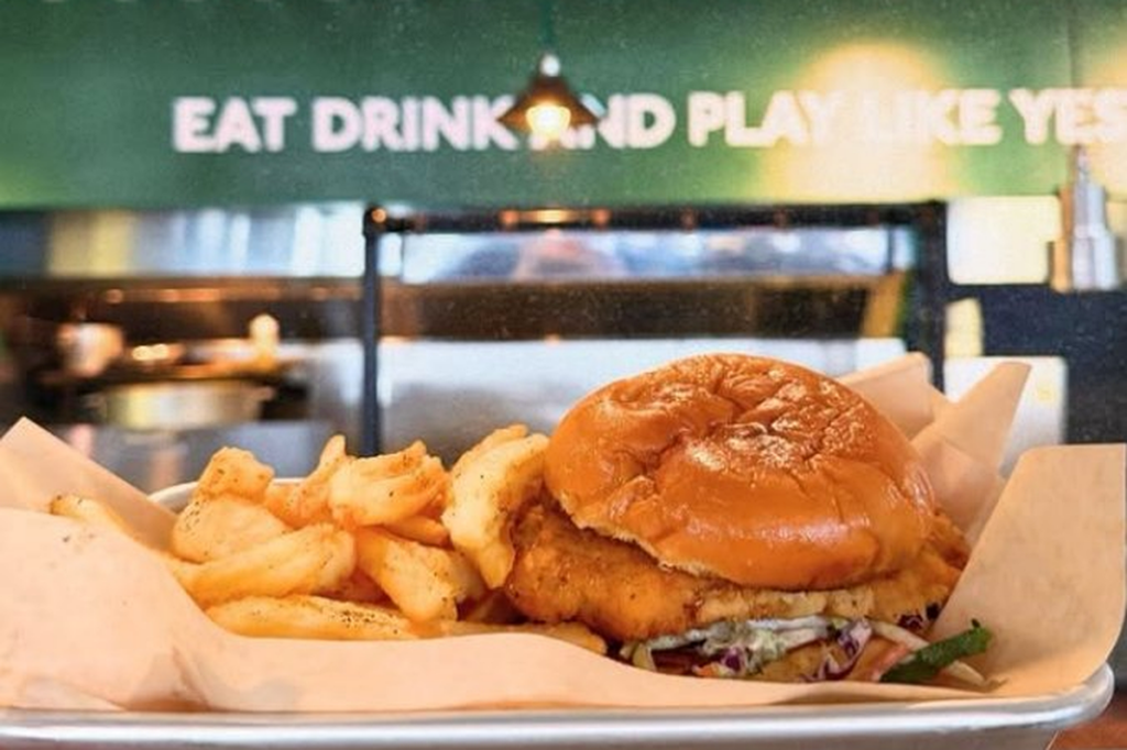 Crispy chicken sandwich and fries served at a golf entertainment venue