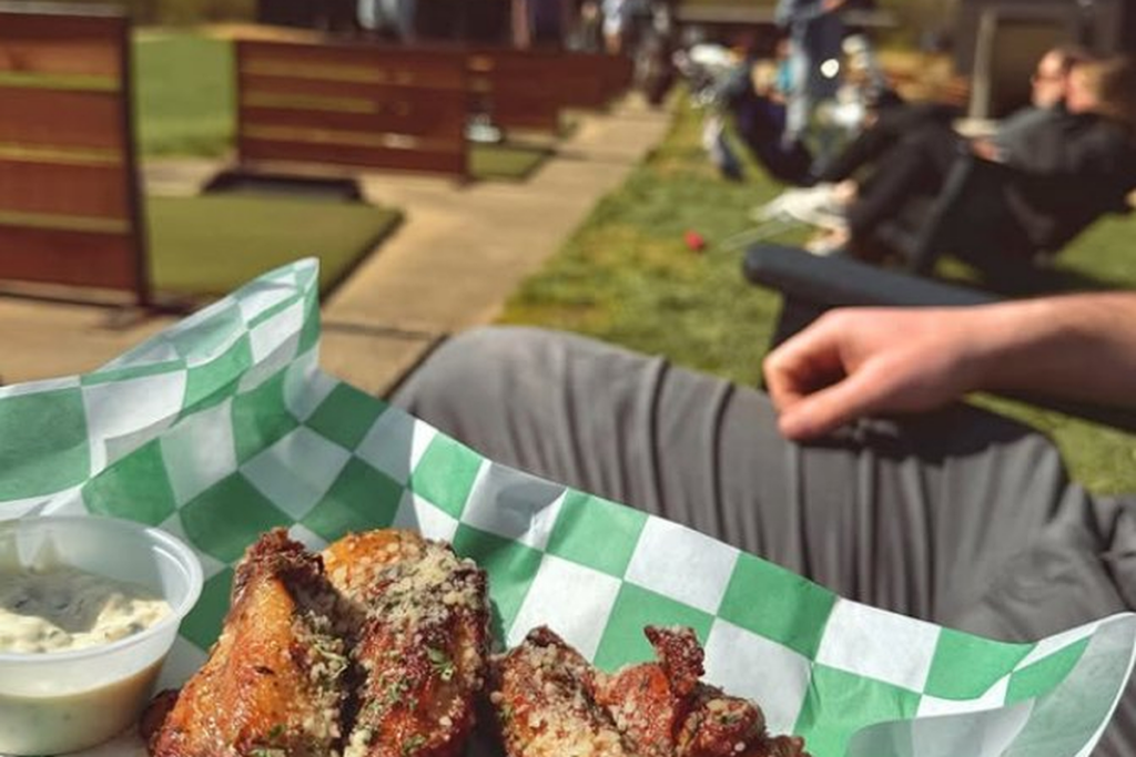 Basket of parmesan wings on a golf entertainment venue patio